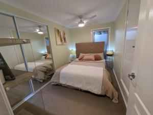 Dormitorio pequeño con cama y espejo en Luxury oasis resort Pet friendly apartment with private pool and spa en Port Macquarie