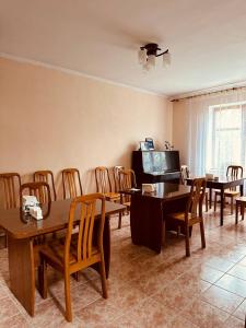 a dining room with tables and chairs and a flat screen tv at Guest House Crocus in Bishkek