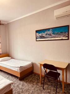 Schlafzimmer mit einem Schreibtisch, einem Bett und einem Stuhl in der Unterkunft Guest House Crocus in Bischkek