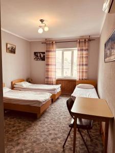 a room with three beds and a table and a window at Guest House Crocus in Bishkek