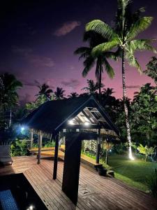 a black umbrella on a deck with palm trees at night at Kaila Na Ua Resort in Korotogo