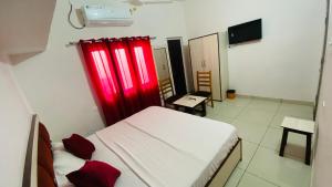 a bedroom with a bed with red curtains in it at Hotel Heartwood City Corbett in Rāmnagar