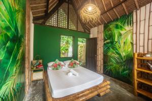 a bedroom with a bed in a room with plants at Fox & The Firefly Cottages in Loboc