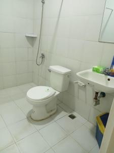a white bathroom with a toilet and a sink at Happy Ripples Beach Resort in Mabilao