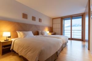 a bedroom with a large bed and a large window at NISEKO Inn of Youtei Raku Suisan in Kutchan