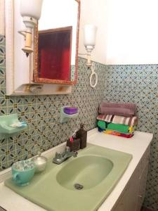 uma casa de banho com um lavatório verde e um espelho em Porta del Sol ~Less than 1 m to center of town! em San German