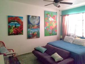 a bedroom with a bed and a couch and paintings at Porta del Sol ~Less than 1 m to center of town! in San Germán
