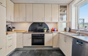 een keuken met witte kasten en een fornuis met oven bij 5 Bedroom Gorgeous Home In Thyborn in Thyborøn