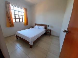 a bedroom with a white bed and a window at BUNGAVILLA House Tarapoto in Tarapoto