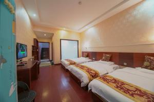 張家界市にあるZhangjiajie Alin Recreation Villaのベッド3台とデスクが備わるホテルルームです。