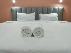 uma cama branca com duas toalhas em โรงแรม เดอะพีช / The Peach hotel em Phetchaburi