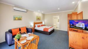 a hotel room with a bed and a living room at Breakout Motor Inn in Cowra