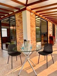 a glass table and two chairs in front of a building at Finca la Flor del Café in Quimbaya
