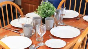 une table en bois avec des assiettes et des verres blancs dans l'établissement Breakout Motor Inn, à Cowra