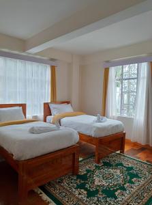 a bedroom with two beds and a window at Shree Niwas in Darjeeling