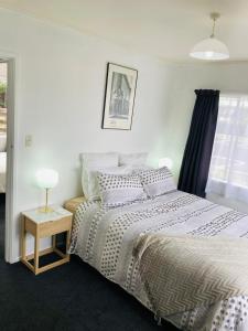a bedroom with a bed and a lamp on a table at 108 by the Lake in Taupo