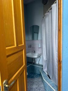 baño con lavabo y cortina de ducha blanca en Guest House Crocus, en Bishkek