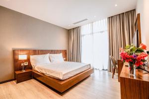 a hotel room with a bed and a vase of flowers at FLC Grand Villa BT35.06 in Sầm Sơn