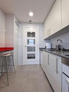a kitchen with white cabinets and a white door at Valdebebas con piscina, gimnasio y garaje in Madrid