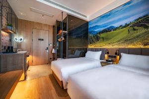 duas camas num quarto de hotel com um quadro na parede em Qiuguo Hotel - Beijing Chaoyang Branch em Pequim