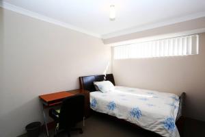 a bedroom with a bed and a desk and a window at Nice and Neat House for your Journey - Renovated in Perth