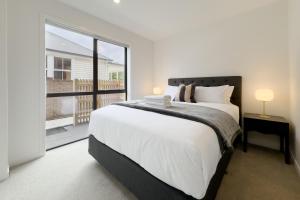 a bedroom with a large bed and a large window at Spacious Townhouse in Epsom School Zone in Auckland