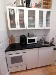 cocina con armarios blancos, microondas y fregadero en Wunderschöne 3 Zimmer Wohnung!, en Hamburgo