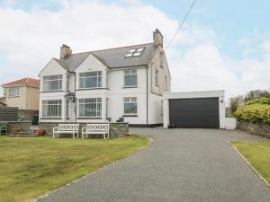 a white house with two benches in the driveway at Gables Retreat in Trearddur