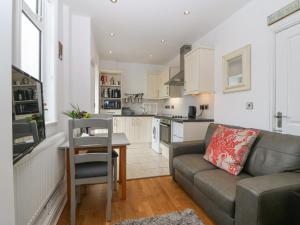 a living room with a couch and a table and a kitchen at Gables Retreat in Trearddur