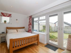 a bedroom with a bed and large windows at Gables Retreat in Trearddur