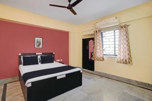 a bedroom with a bed with red walls and a window at OYO 27 DEGREE HOTEL in Jamshedpur