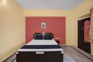 a bedroom with a bed with a red wall at OYO 27 DEGREE HOTEL in Jamshedpur