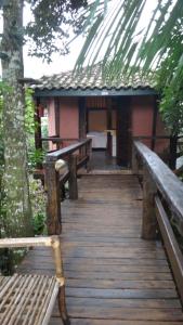 a wooden walkway leading to a house with benches at Chalés Catavento in Maresias