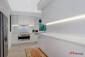 a white kitchen with white cabinets and appliances at MetaWise Luxury Haven 4 Bed in Central Double Bay in Sydney