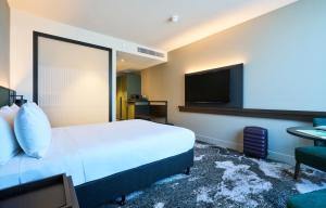 um quarto de hotel com uma cama e uma televisão de ecrã plano em Novotel Melbourne Airport em Melbourne