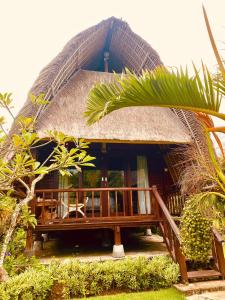 a building with a thatched roof with a porch at Harta Lembongan Villas in Nusa Lembongan