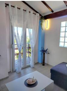 a living room with white curtains and a table at Thanos Guesthouse Corfu in Áyioi Dhéka