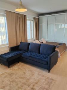a living room with a blue couch and a bed at Keskustan tyylikkäin studio omalla autopaikalla in Lappeenranta