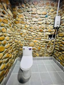 a stone bathroom with a toilet in front of a stone wall at HOLY VILLA A Frame 3beds 1sofa bed 1bathroom in Kampot