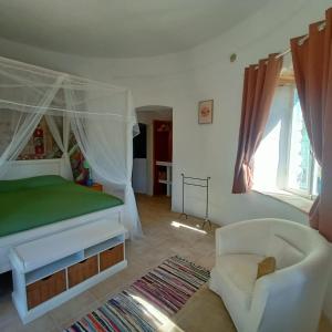 ein Schlafzimmer mit einem Bett und einem Stuhl darin in der Unterkunft Pietra Bianca in Koríthion