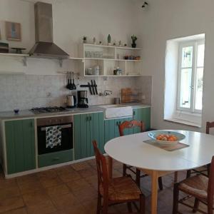eine Küche mit grünen Schränken und einem Tisch mit einer Schale Obst in der Unterkunft Pietra Bianca in Koríthion
