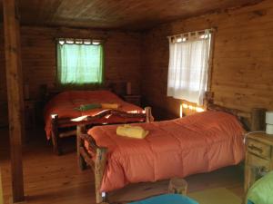 1 dormitorio con 2 camas en una cabaña de madera en La Casa Escondida, en Punta Arenas