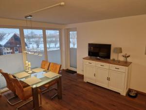 ein Wohnzimmer mit einem Esstisch und einem TV in der Unterkunft Nelly Modern retreat in Horumersiel