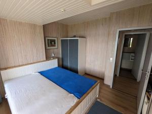 a small room with a bed with a blue blanket at Schleipanorama Modern retreat in Brodersby