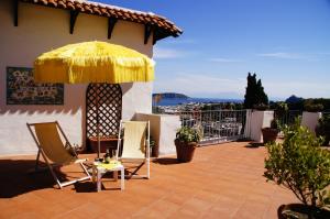 um pátio com cadeiras e um guarda-sol amarelo em Hotel Don Pedro em Ischia