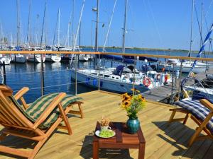 a deck with two chairs and a table and boats at Premium houseboat on the lake in Heiligenhafen