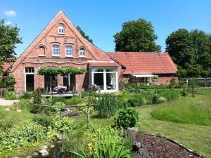 een bakstenen huis met een tuin ervoor bij Rose Cottage Comfortable holiday residence in Petershagen