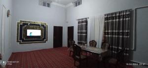 a dining room with a table and a tv on a wall at Khiva Saodat Guest House in Khiva
