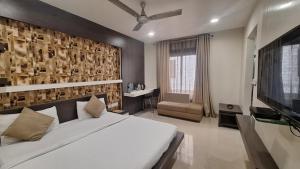 a bedroom with a large bed and a flat screen tv at Hotel Alankar Palace in Bhopal