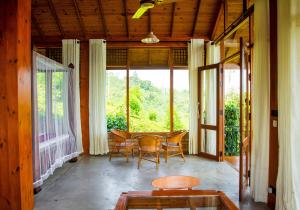 eine abgeschirmte Veranda mit einem Tisch und Stühlen in der Unterkunft Tea Forest Eco Lodge in Kandy